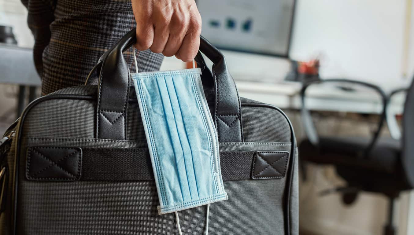 man-carrying-laptop-bag-and-mask