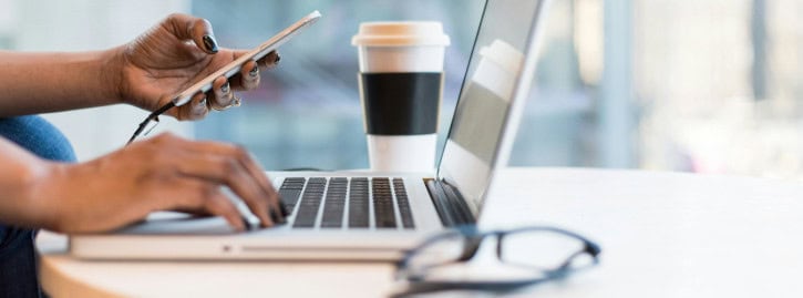 laptop with hands holding a mobile phone
