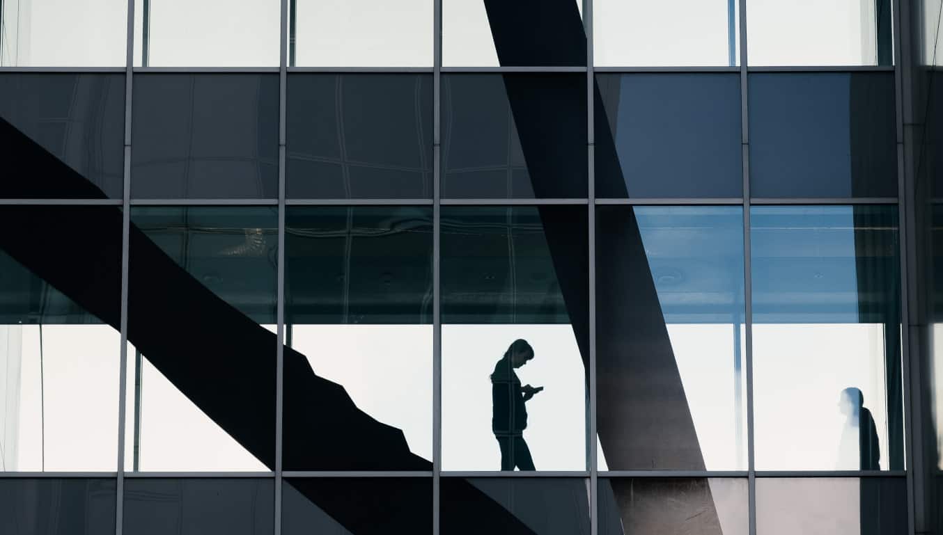 office building with a shadow of a person walking down stairs on their phone