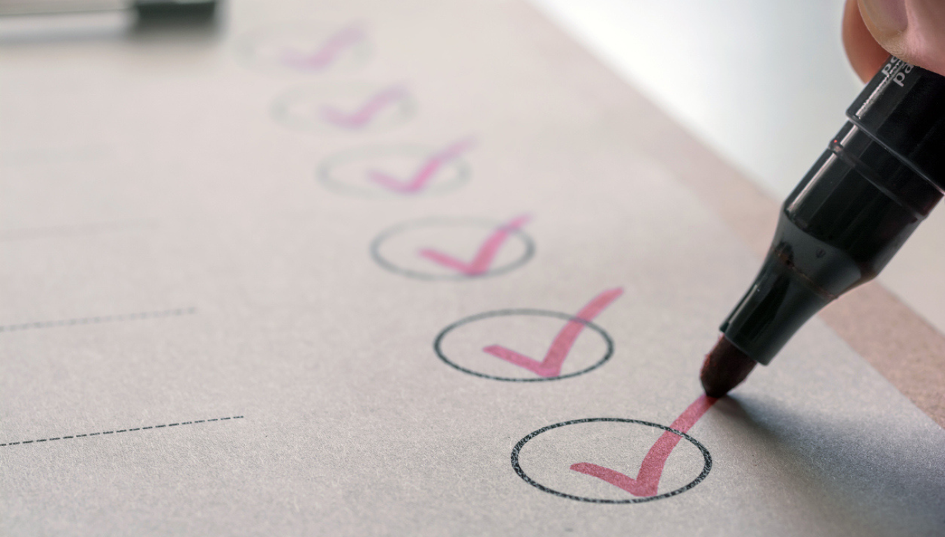 checklist with red ticks in circles and a person holding a pen