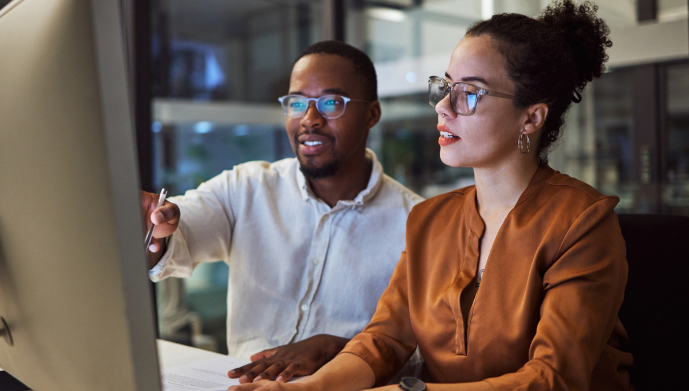 Night training, teamwork and employees planning marketing strategy in a dark office on computer at work. Corporate African man and woman talking about business collaboration during overtime