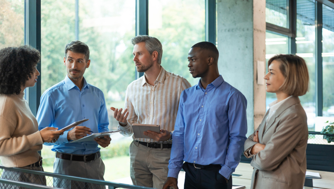 Four business people discussing work together using a tablet in a modern office