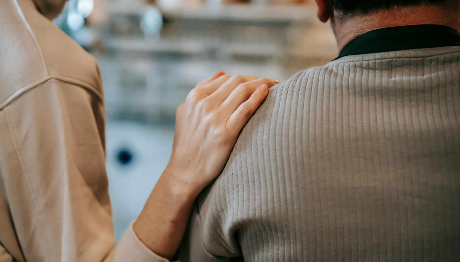 Unrecognizable woman touching shoulder of man at home
