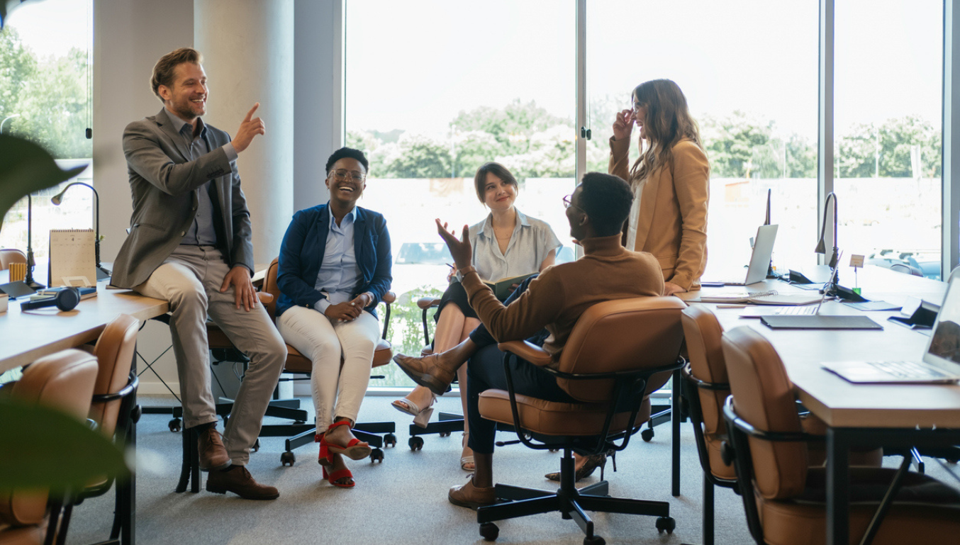 people sat at a desk in an office chatting