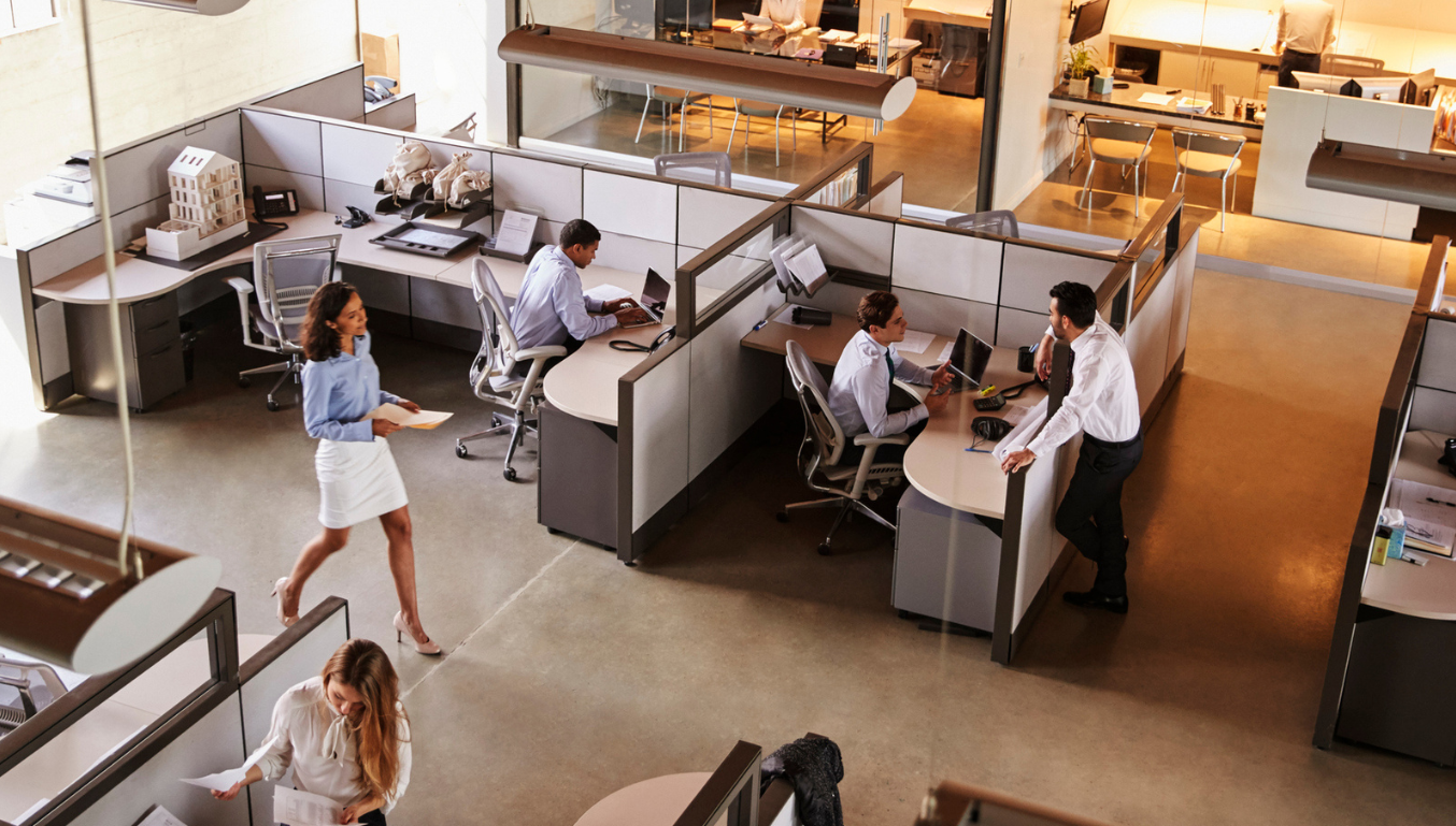 people in an office some at desks some walking around