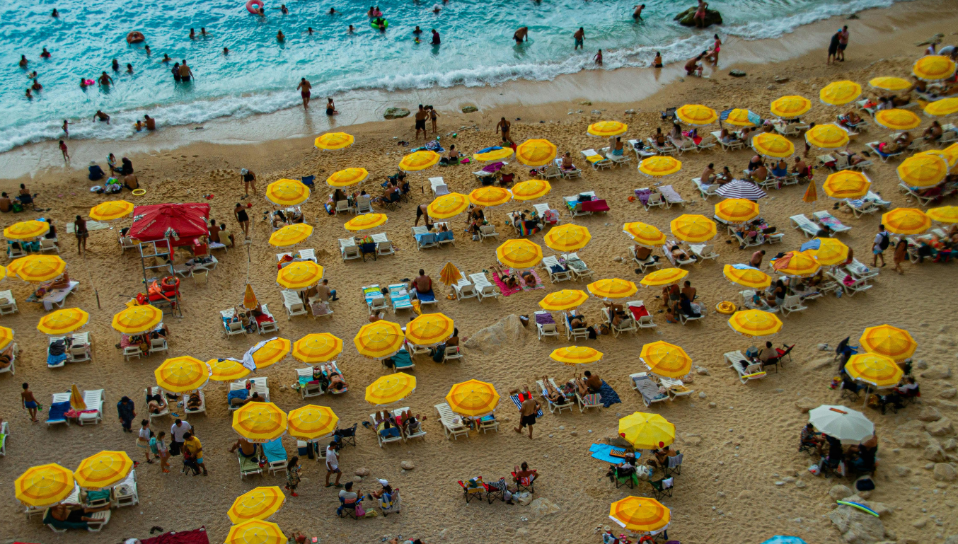A vibrant aerial view of sunbathers and yellow umbrellas on a sandy beach