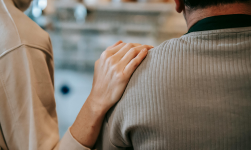 Unrecognizable woman touching shoulder of man at home