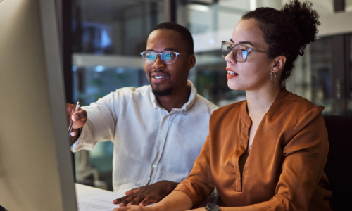 Night training, teamwork and employees planning marketing strategy in a dark office on computer at work. Corporate African man and woman talking about business collaboration during overtime