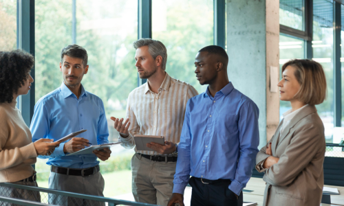 Four business people discussing work together using a tablet in a modern office