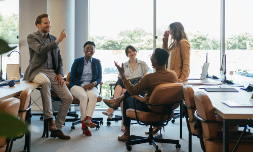 people sat at a desk in an office chatting