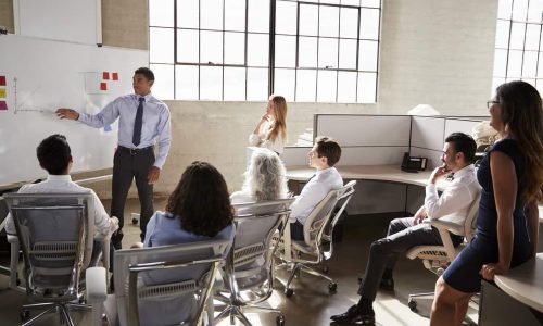 Business group watching a male colleague give a presentation
