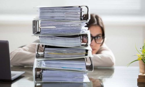 Businesswoman Hiding Behind The Folders Stack