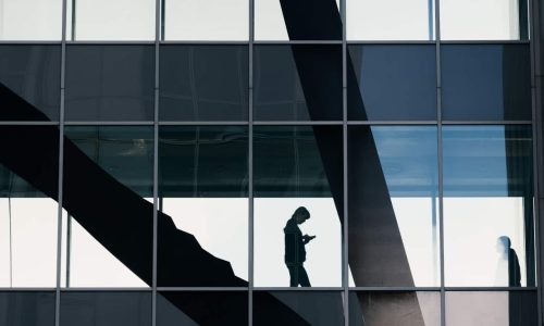 office building with a shadow of a person walking down stairs on their phone